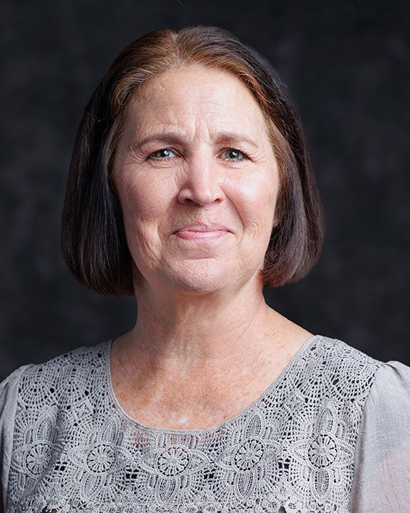 a woman with short brown hair wearing a lace top